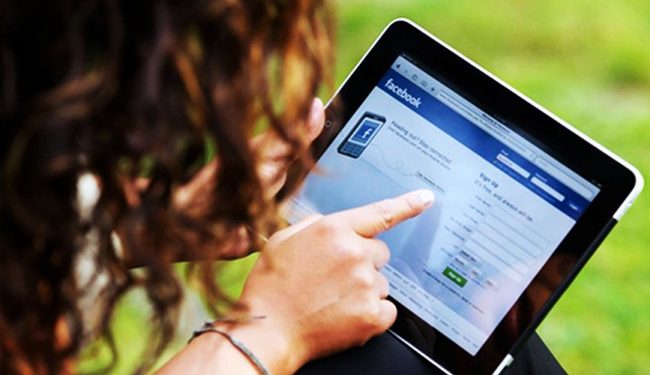 BR9RH9 Close up of a woman hand holding an iPad checking her Facebook page